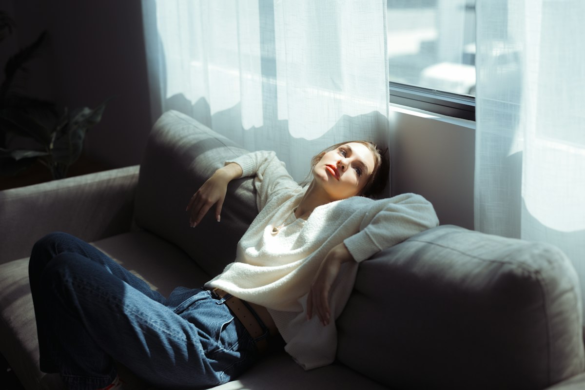 Seseorang bersantai di tempat tidur dengan cahaya lembut pagi hari